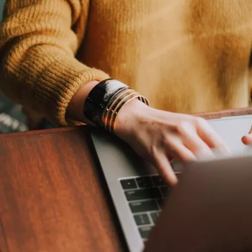 Persona con manos en el ordenador trabajando desde casa